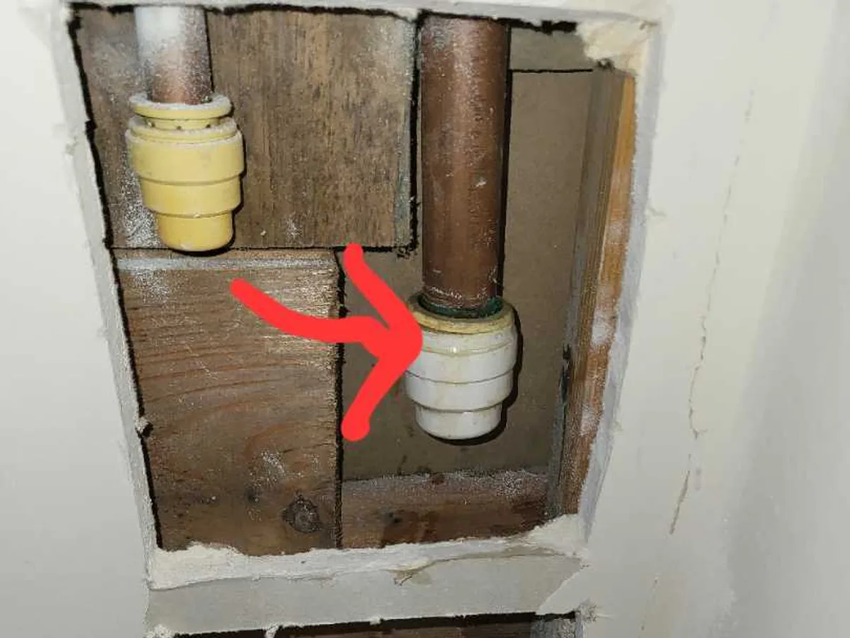 Push-fit connector joining a copper pipe inside an exposed wall void during an internal mains leak detection at a property in WF8