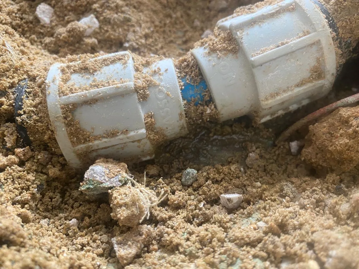 Exposed compression fittings on a blue MDPE pipe joint uncovered during a swimming pool circuit leak detection at a property in Harrow