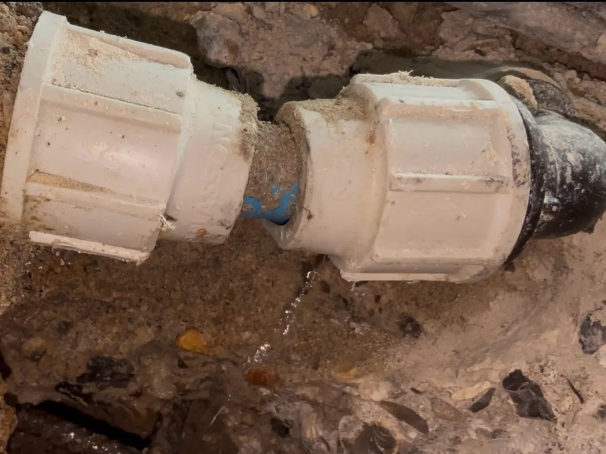 Leaking compression fitting on an excavated pool pipe with water seeping from the joint at a property in Harrow