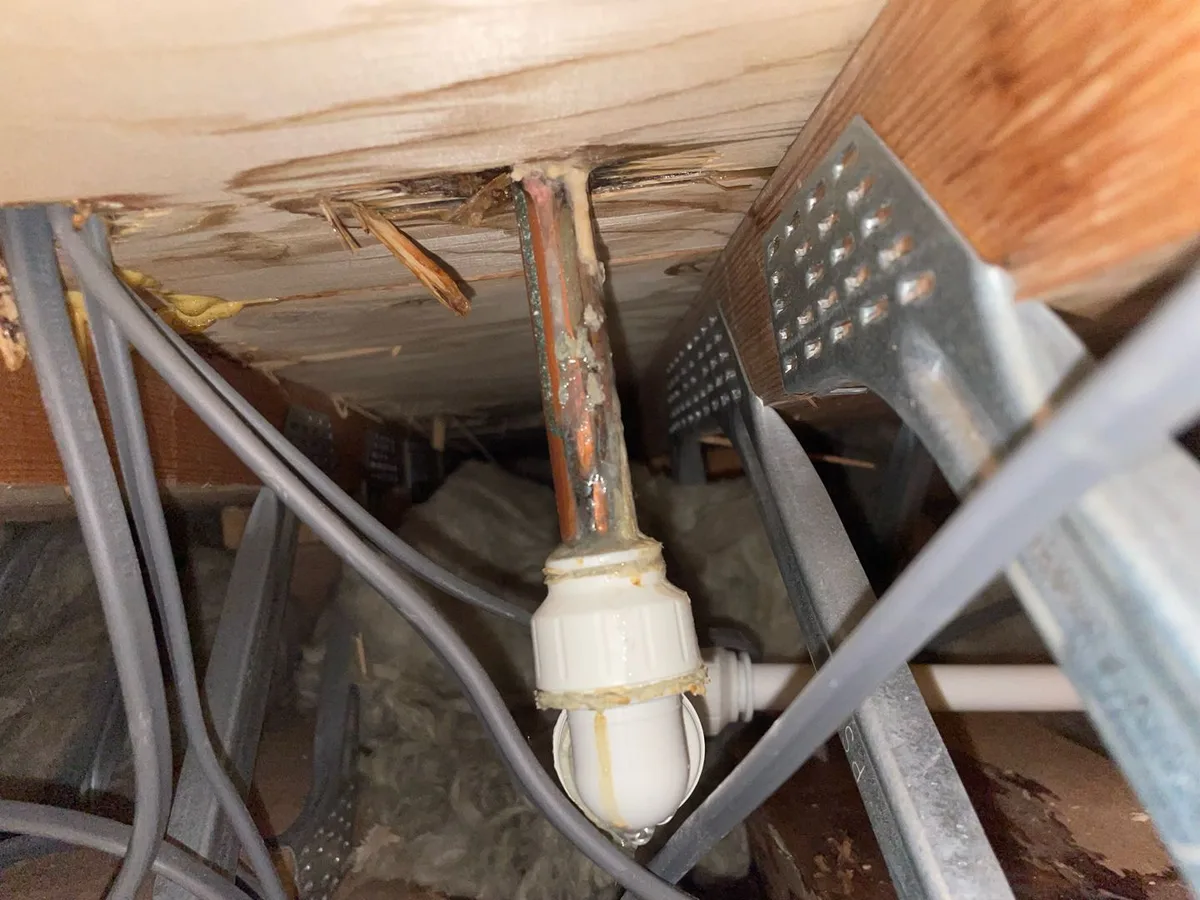 Corroded copper pipe with compression fitting inside an underfloor void during a hot water leak detection survey at a property in Uxbridge