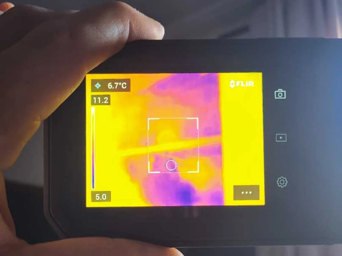 FLIR thermal imaging camera display showing heat variation between 5.0°C and 11.2°C during a water mains leak detection survey at a property in ST3