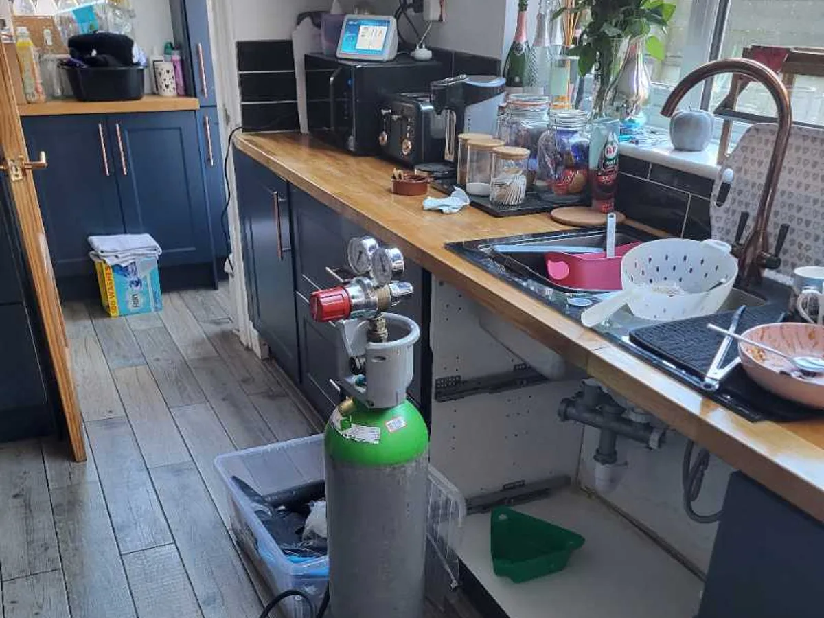 Tracer gas cylinder with pressure regulator positioned in kitchen during an internal mains leak detection survey at a property in ST3