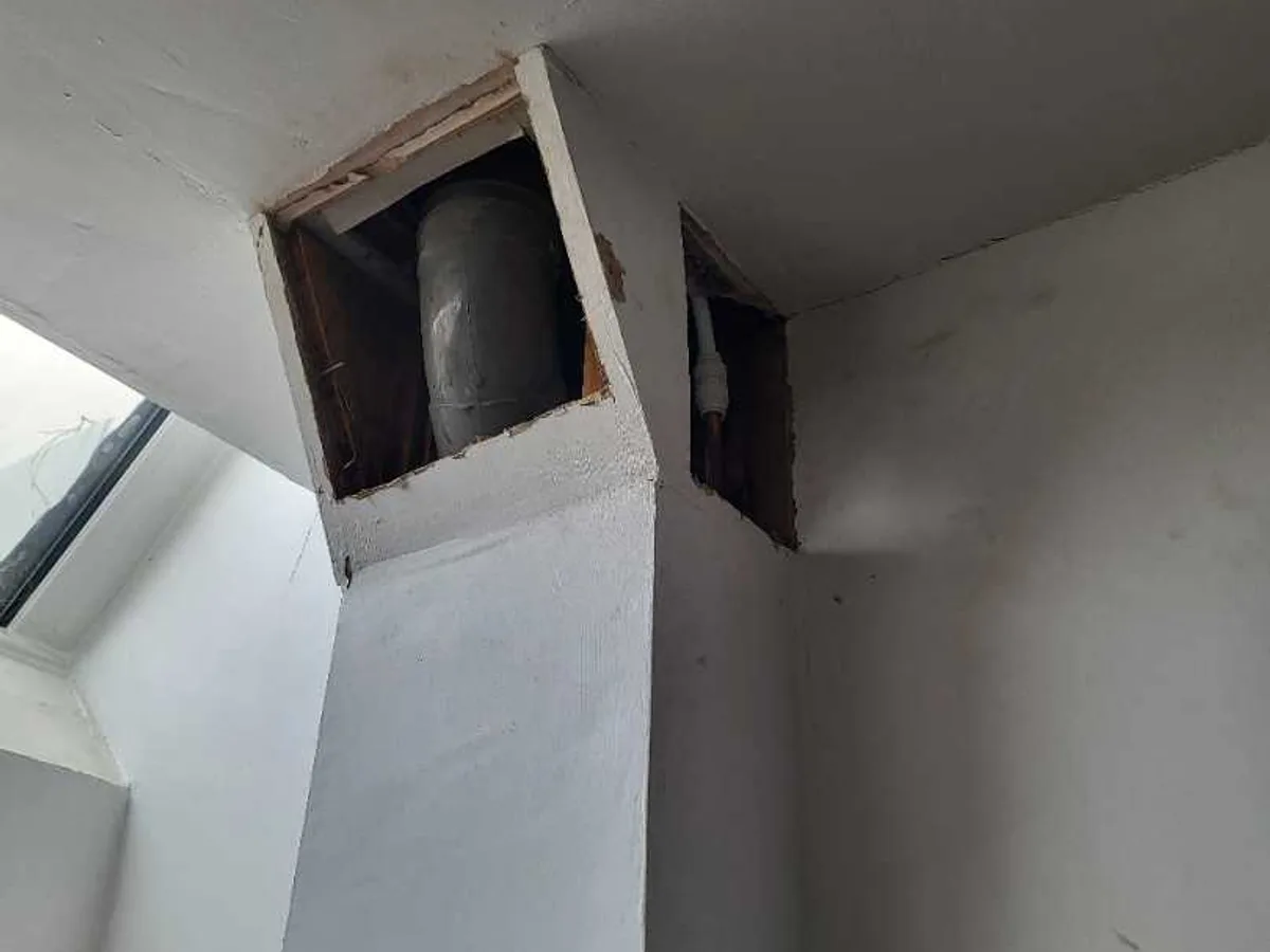 Opened ceiling void exposing a large soil pipe and smaller pipework during an internal mains leak detection survey at a property in ST3