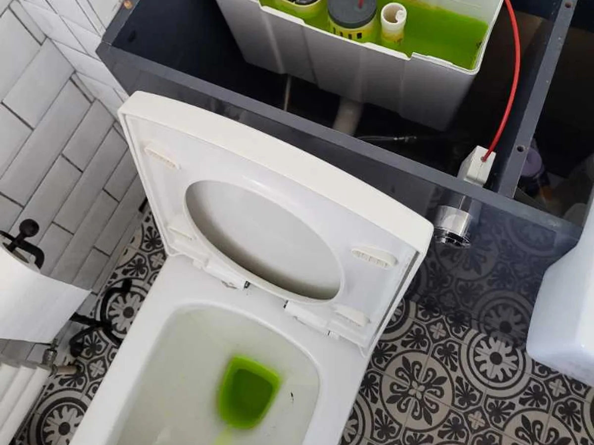Green tracer dye visible in toilet bowl with open cistern during an internal mains leak detection survey at a property in ST3