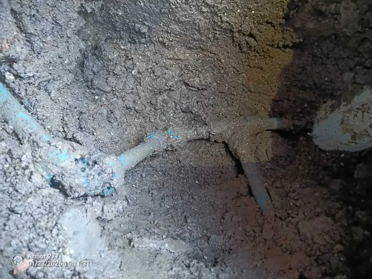 Exposed underground pipe joint uncovered during a mains leak detection excavation at a property in SN8