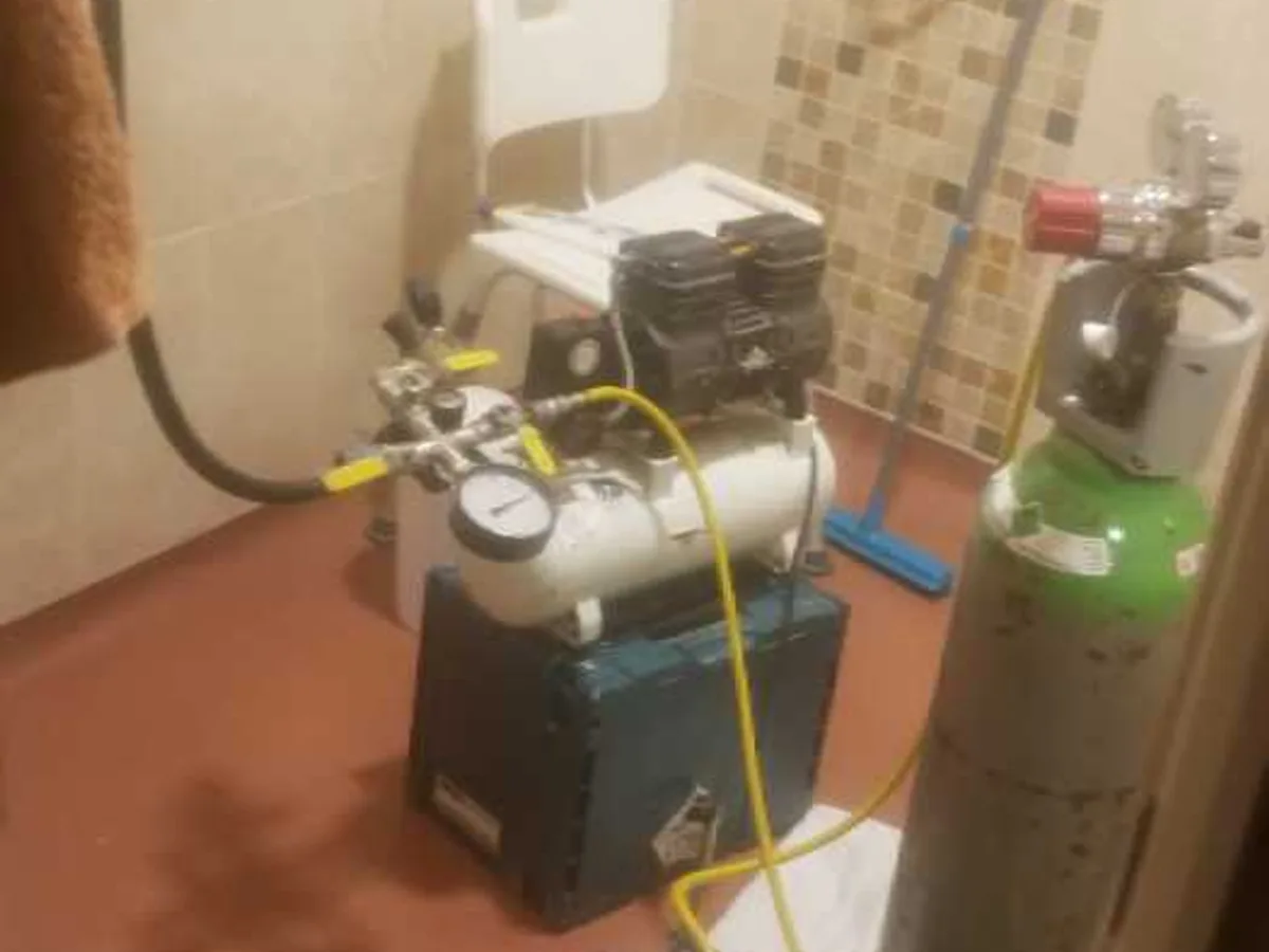 air compressor and tracer gas cylinder set up in bathroom during leak detection