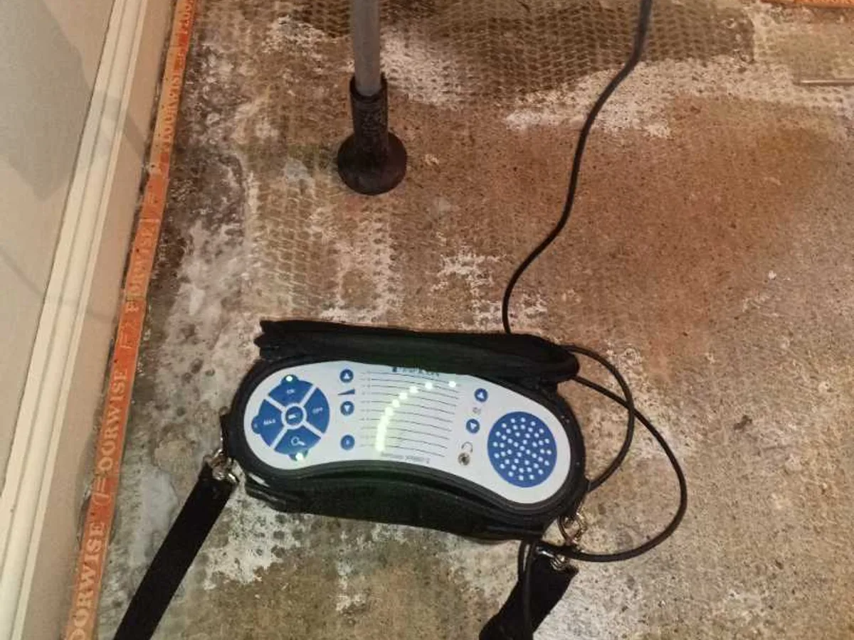 tracer gas detector and probe on damp hallway floor during leak detection