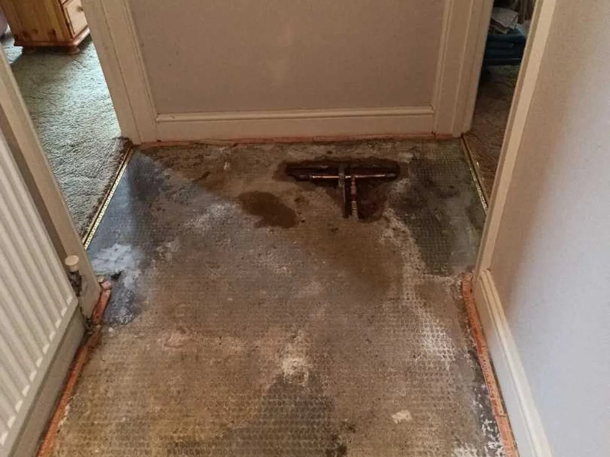 hallway floor with repaired copper tee visible and carpet removed after works completed
