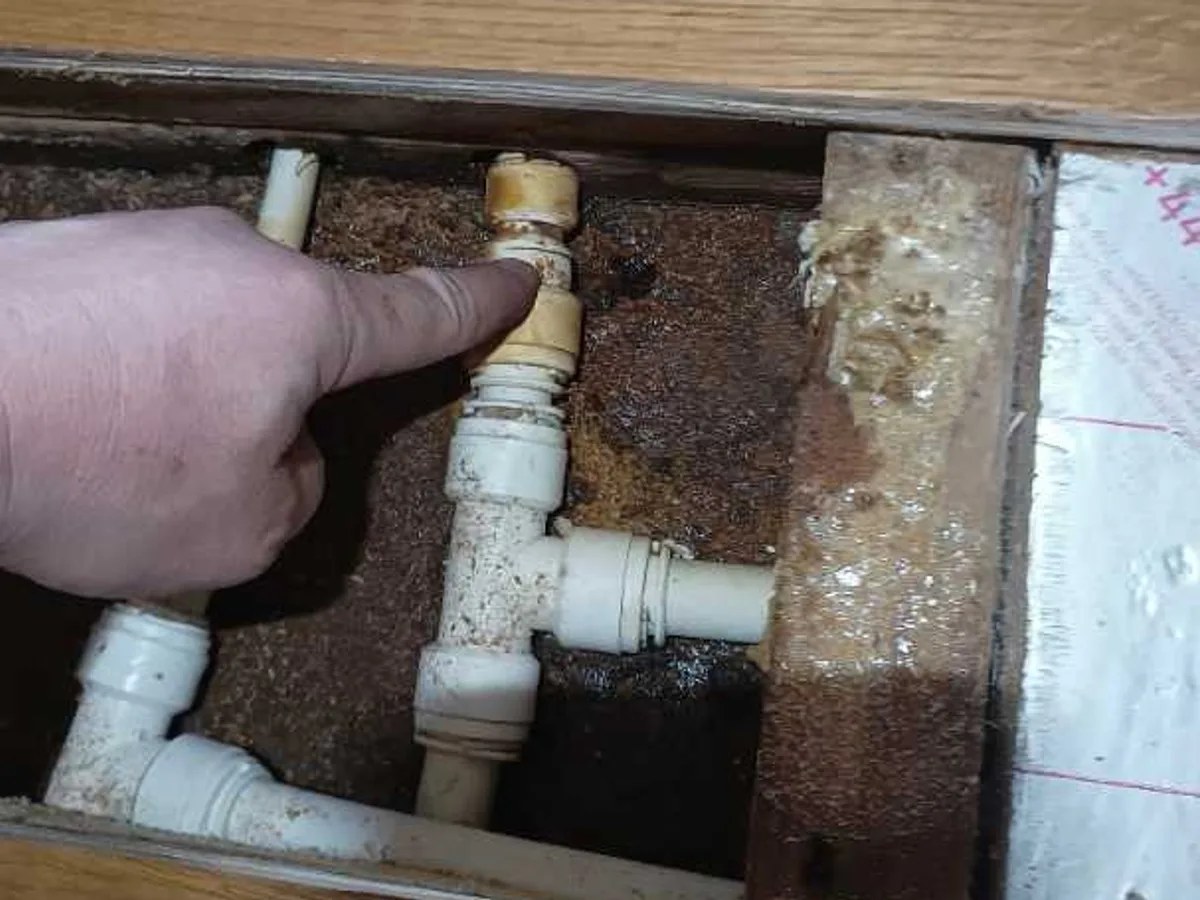 leak located at cracked push-fit fitting beneath lifted wooden floorboards in living room