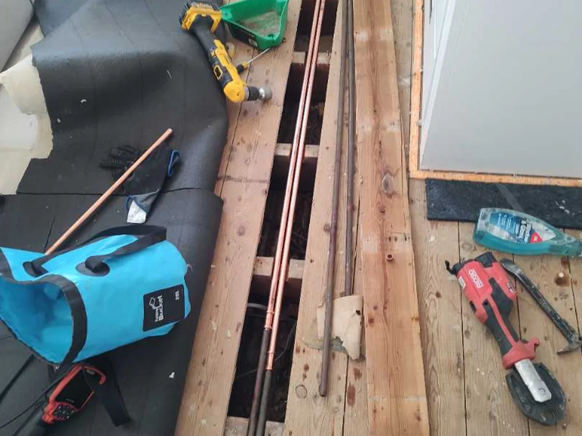 repair in progress with new copper pipe lengths laid alongside opened bedroom floorboards