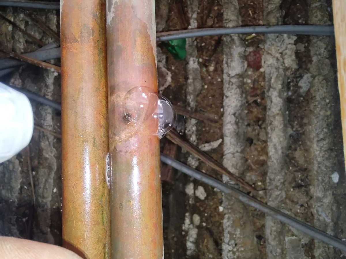 fault identified at pinhole leak on copper heating pipe caused by nail penetration below floorboards — leak located at