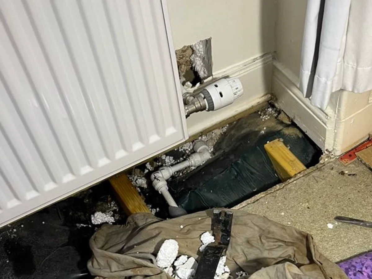 repair in progress on rodent-damaged central heating pipework beneath bedroom radiator