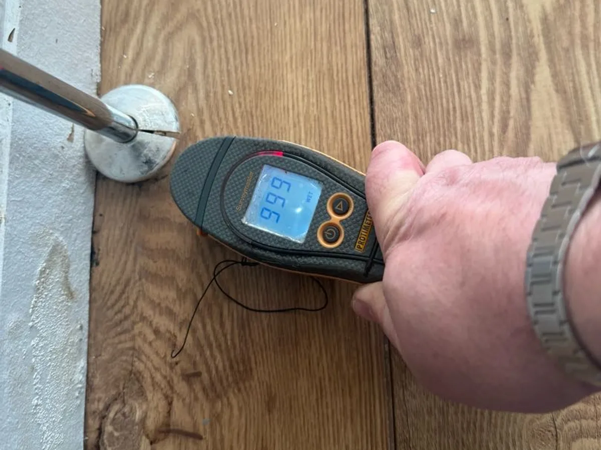 damp meter in use on laminate flooring during leak detection investigation