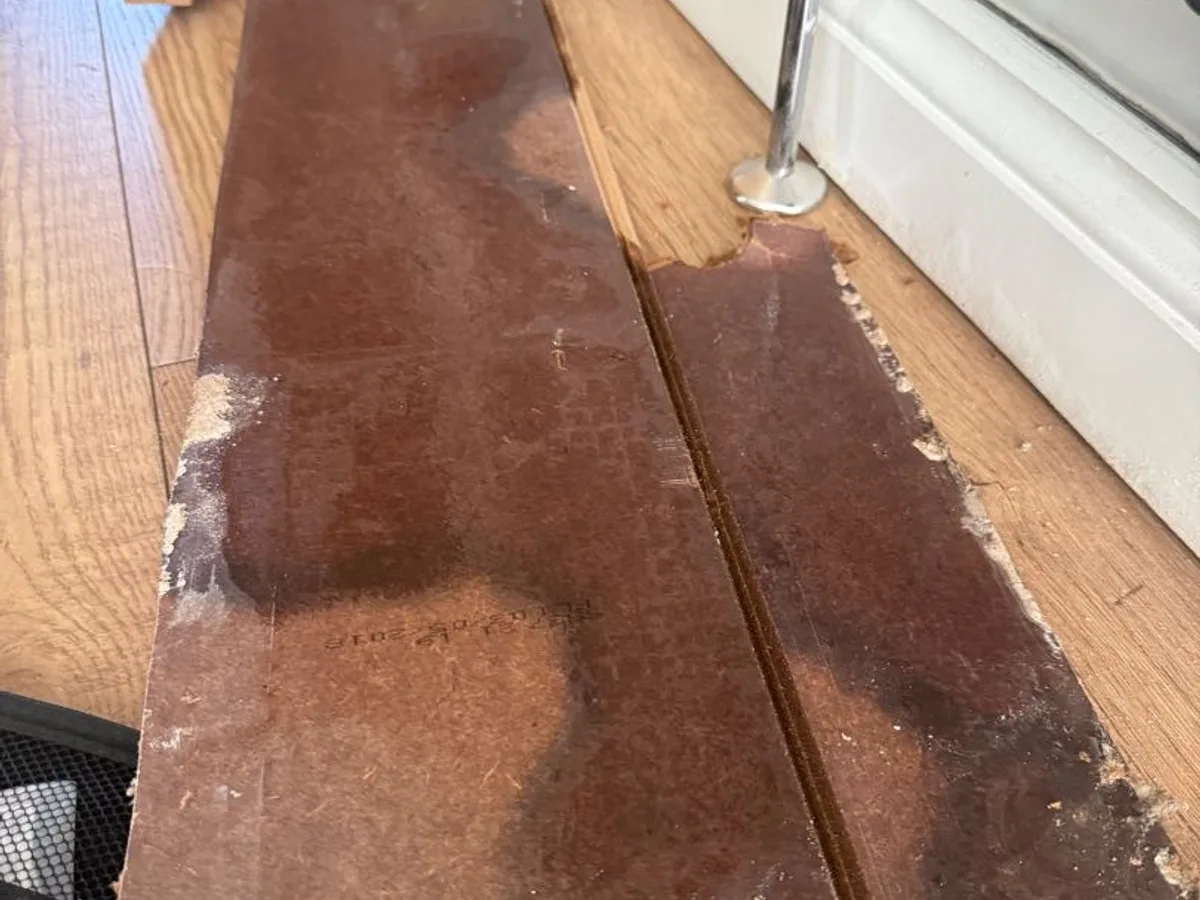 wet and stained underside of lifted laminate boards during leak detection survey
