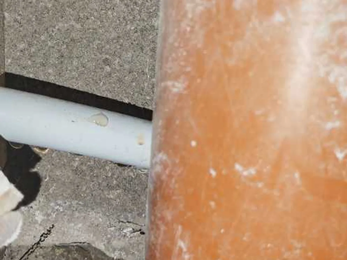 fault exposed at underfloor heating flow and return pipes behind studwork with water damage visible
