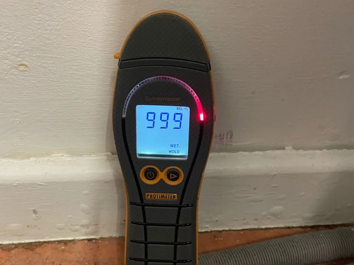 moisture meter reading 999 on kitchen wall at skirting level during leak detection survey
