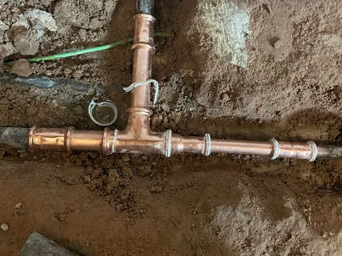 new copper press fittings installed at tee joint in excavated kitchen floor as repair completed