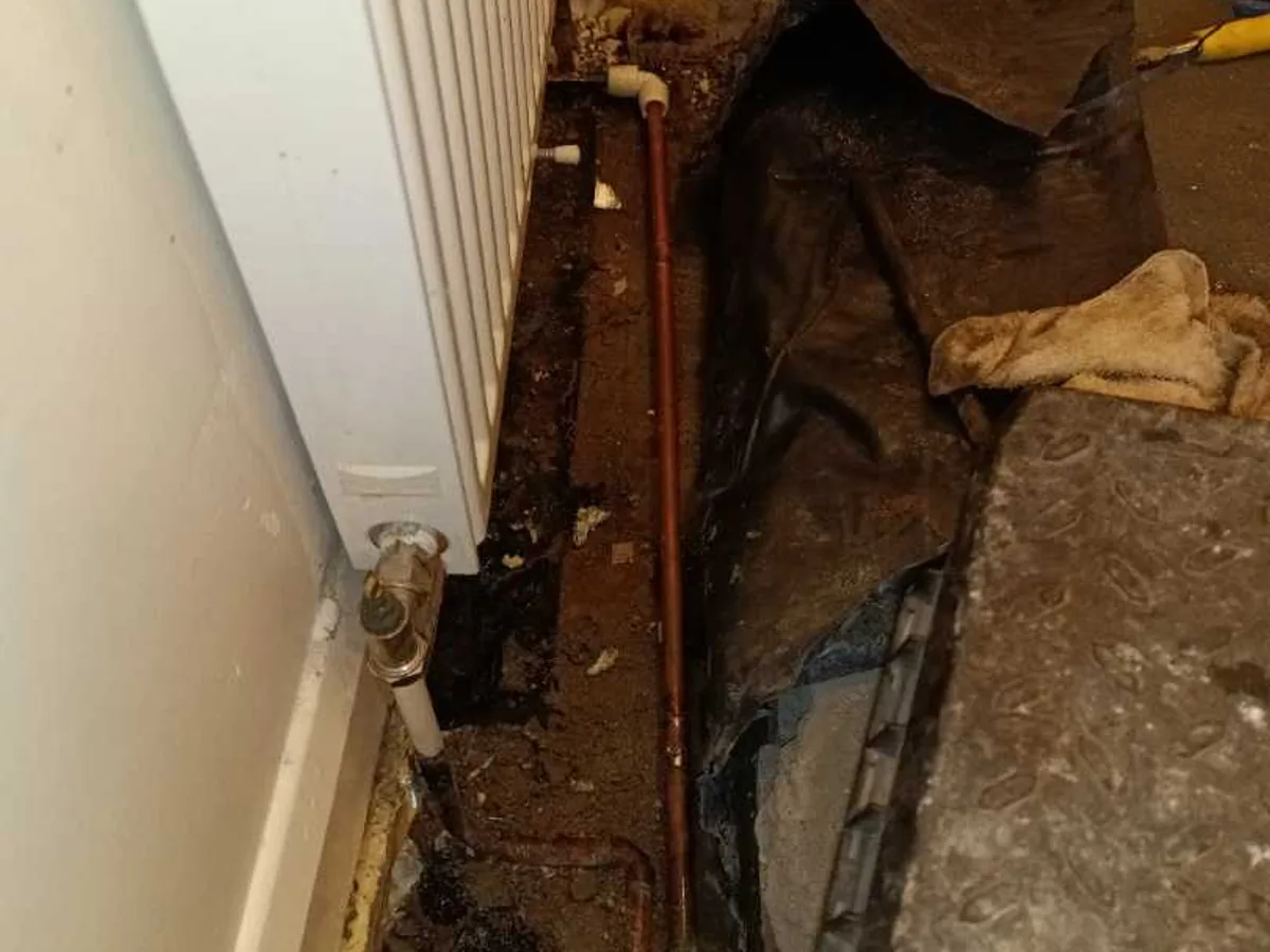 new 15mm copper pipe with push-fit connectors installed as repair completed beneath hallway radiator