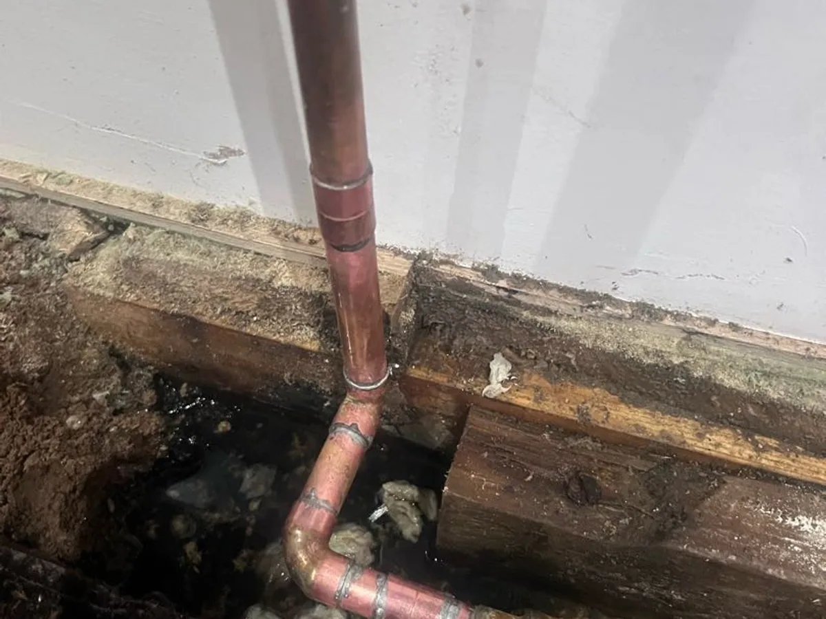 new 15mm copper pipe and elbow fittings installed beneath floorboards as repair completed
