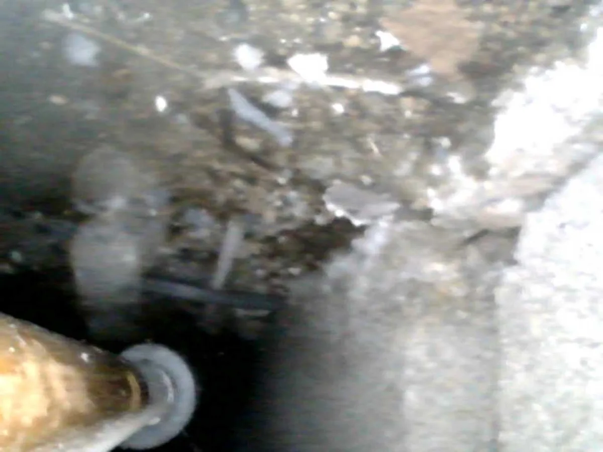 leak located beneath hallway floor showing wet soil and debris around heating pipework — leak located at