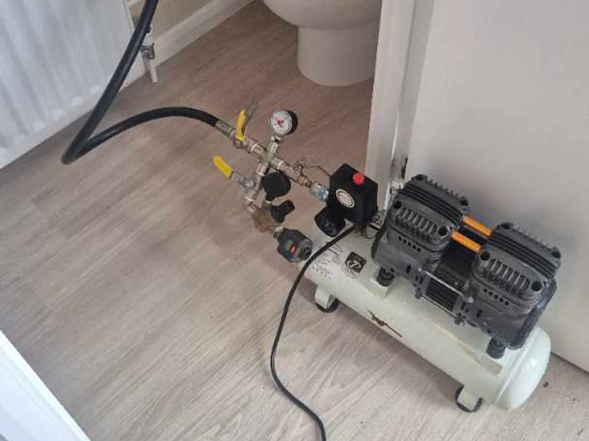 air compressor with pressure gauge connected to heating system during leak detection