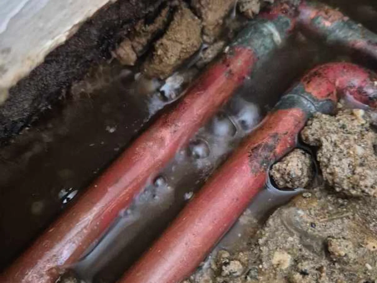 fault identified at waterlogged 15mm copper heating pipe and elbow joint beneath floor — leak located at