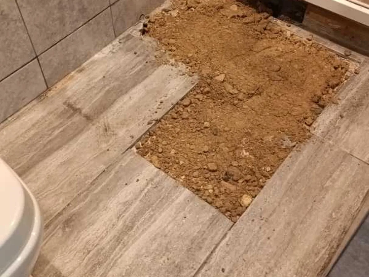 garage bathroom floor reinstated after repair with excavation backfilled beside shower enclosure