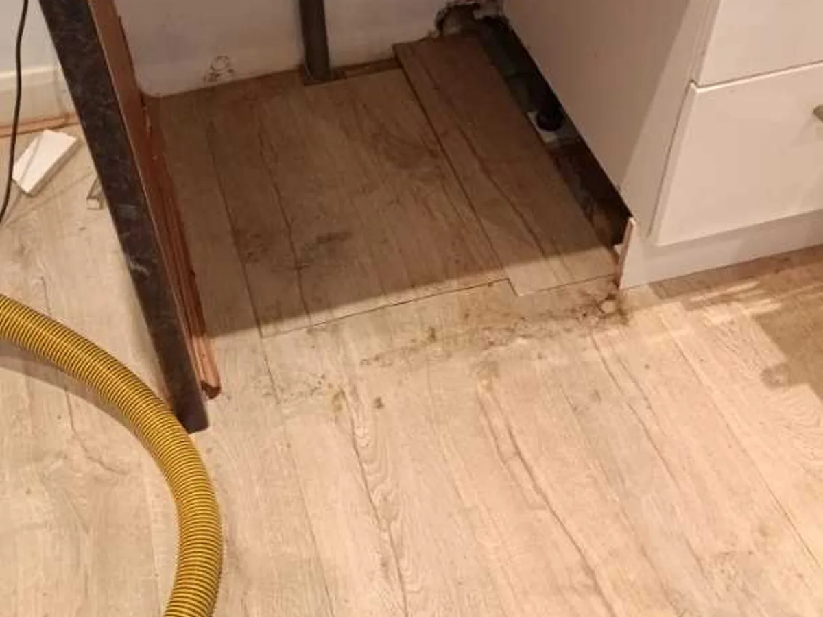 repair completed under kitchen worktop with pipework exposed and floor opening cleared