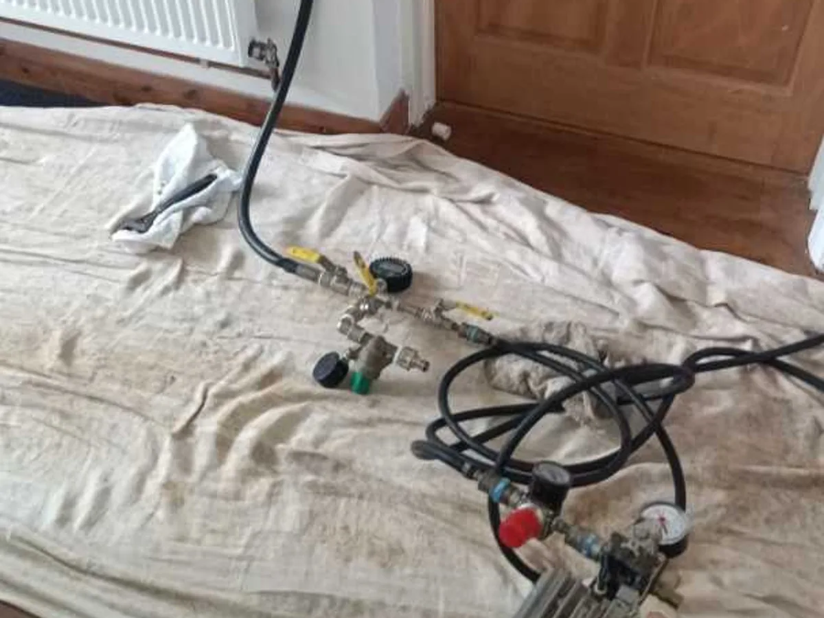 tracer gas manifold and compressor laid out beside radiator during leak detection
