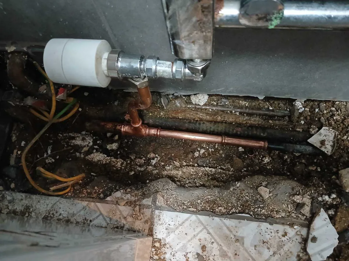 new copper tee and section of pipe installed as repair completed beneath shower room floor