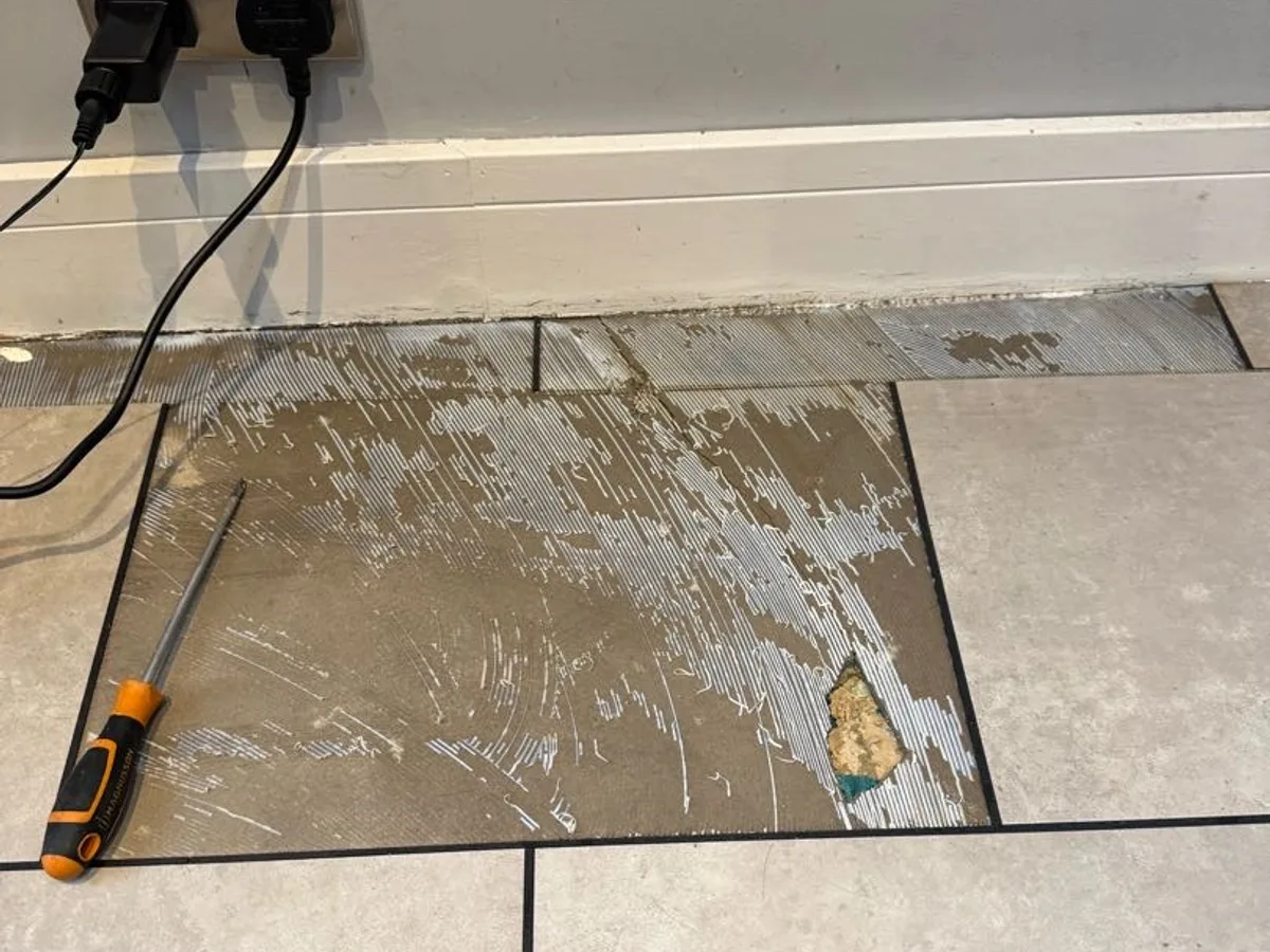 floor tile lifted to reveal wet screed beneath during leak detection investigation