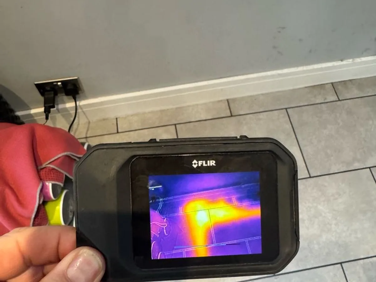 thermal imaging camera screen showing heat patch beneath tiled floor during leak detection