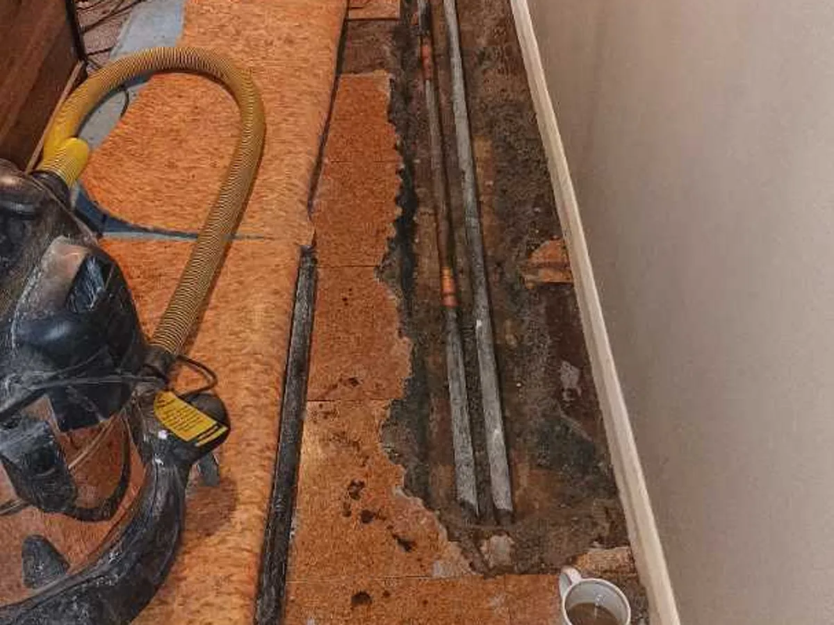 repair in progress with concrete floor cut open exposing heating pipework in hallway doorway area