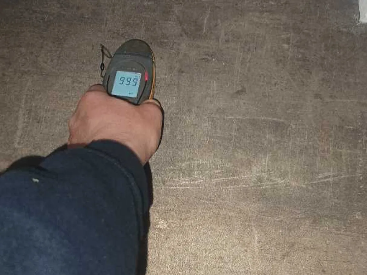 damp meter reading 99.9 on concrete floor surface during leak detection