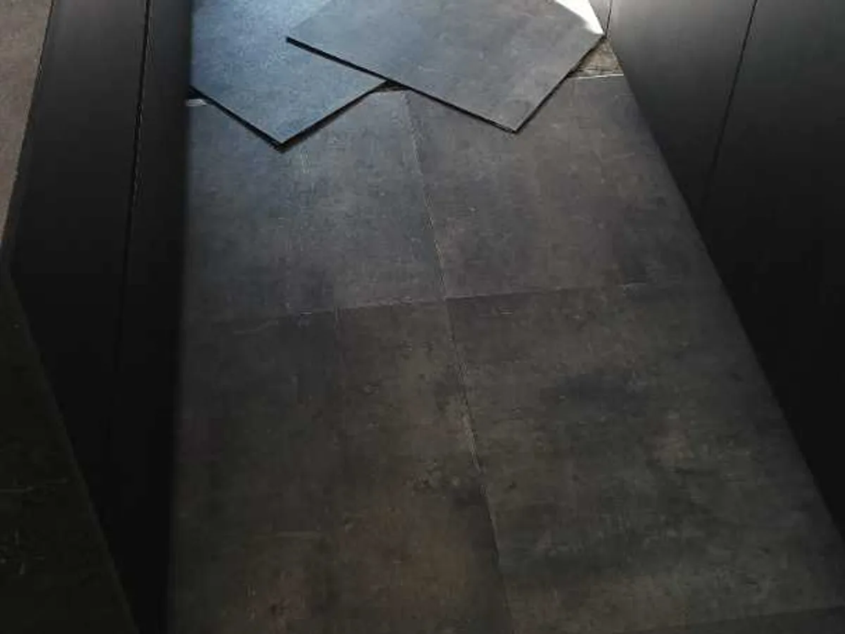 kitchen vinyl floor tiles being relaid between island and units after works completed