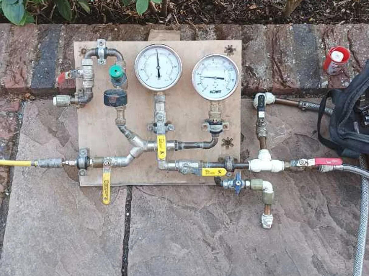 dual-gauge pressure test kit connected to heating system pipework during leak detection