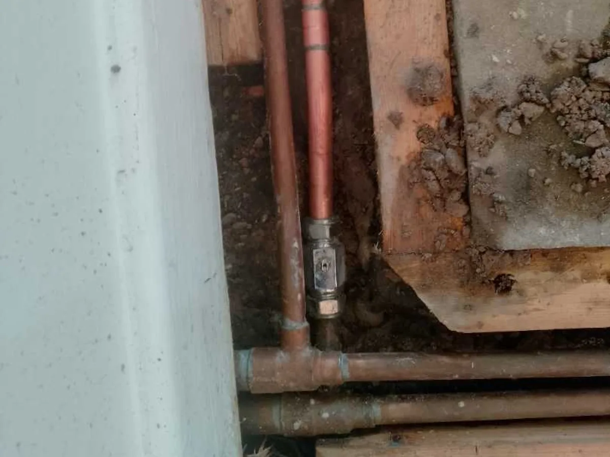 new compression isolation valve fitted to copper heating pipework as repair completed beneath hallway floor