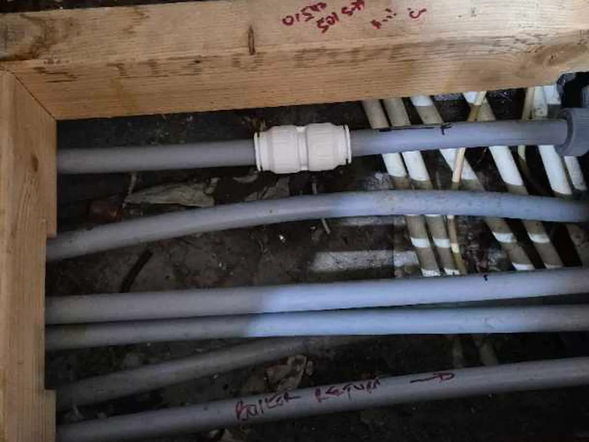 heating pipework beneath boiler area reinstated after repair with new push-fit connector visible