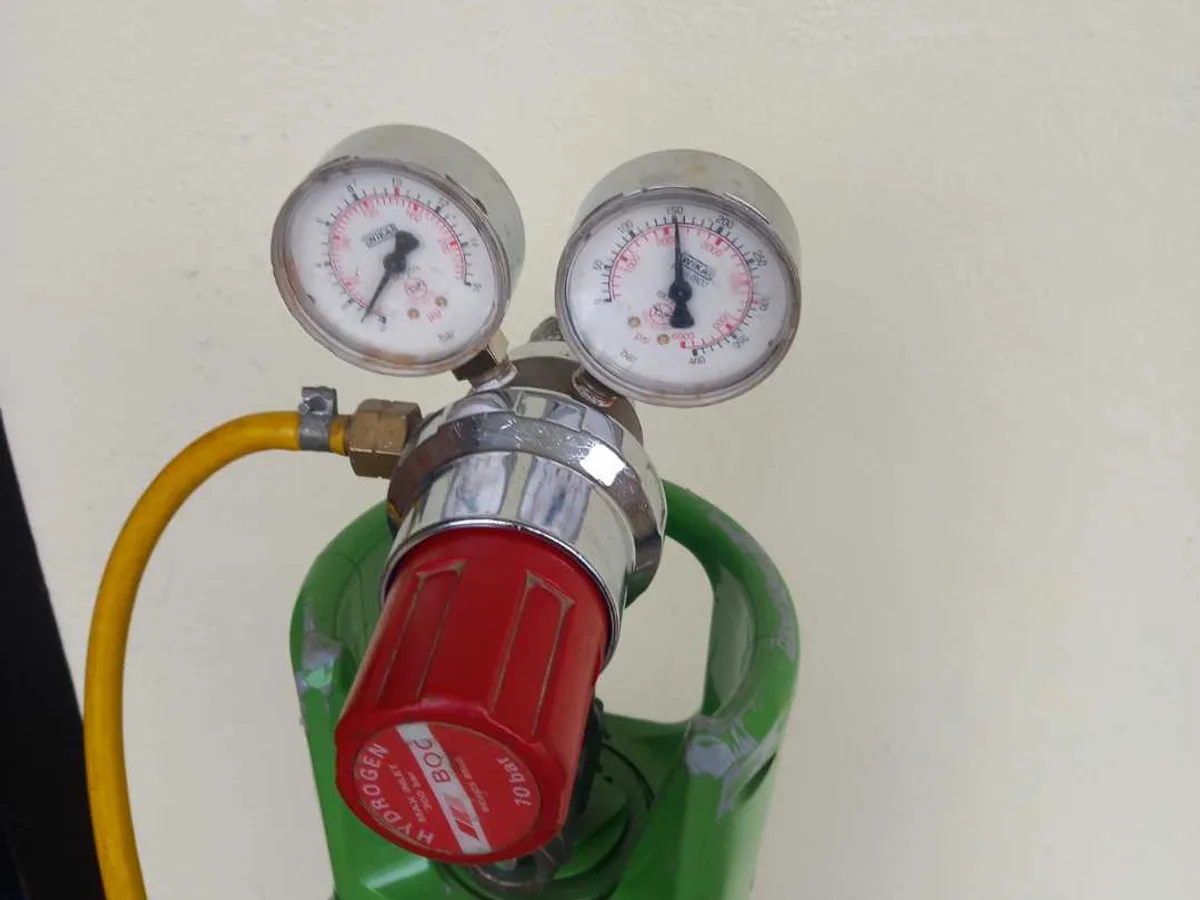tracer gas cylinder with dual-gauge regulator in use during leak detection