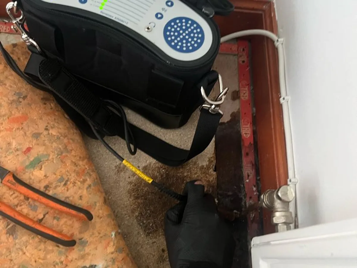 tracer gas detection unit held at radiator valve connection during leak detection