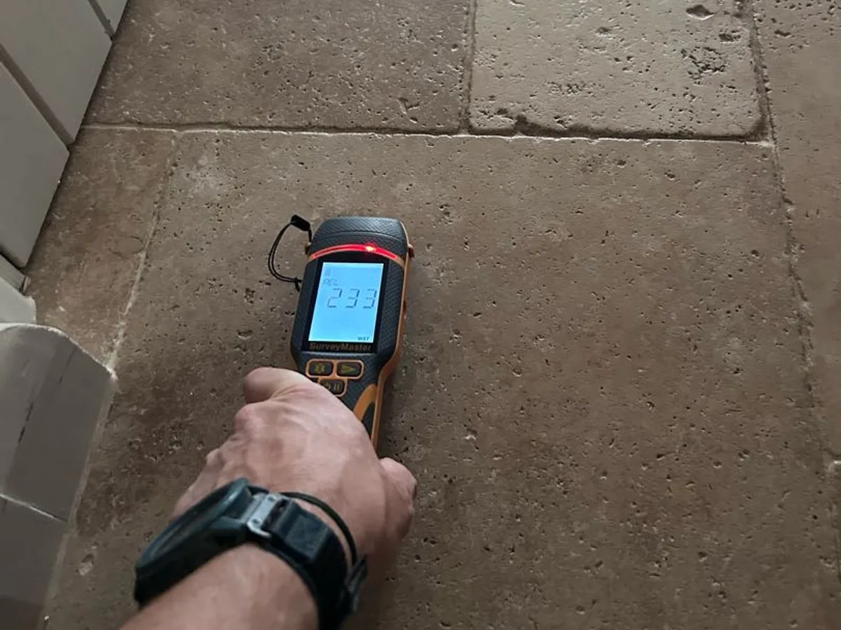 damp meter being used on stone tile floor during leak detection survey
