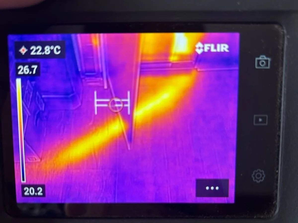thermal imaging camera screen showing heated pipe runs beneath floor during leak detection
