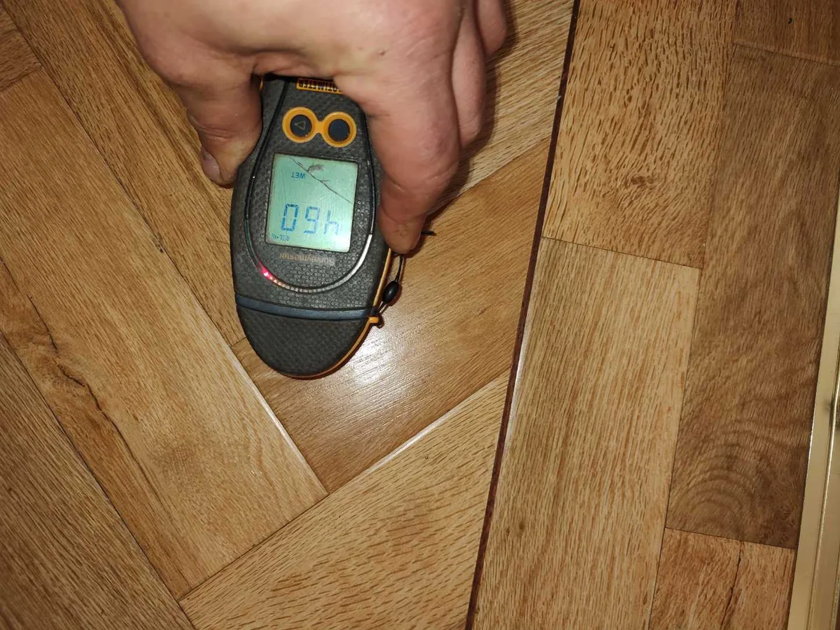 damp meter showing elevated moisture reading on parquet floor during leak detection