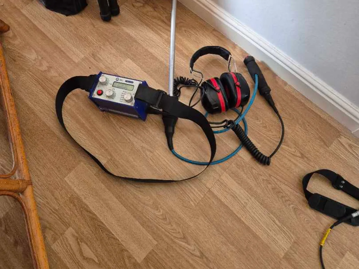 acoustic listening device with headphones and probe beside radiator during leak detection