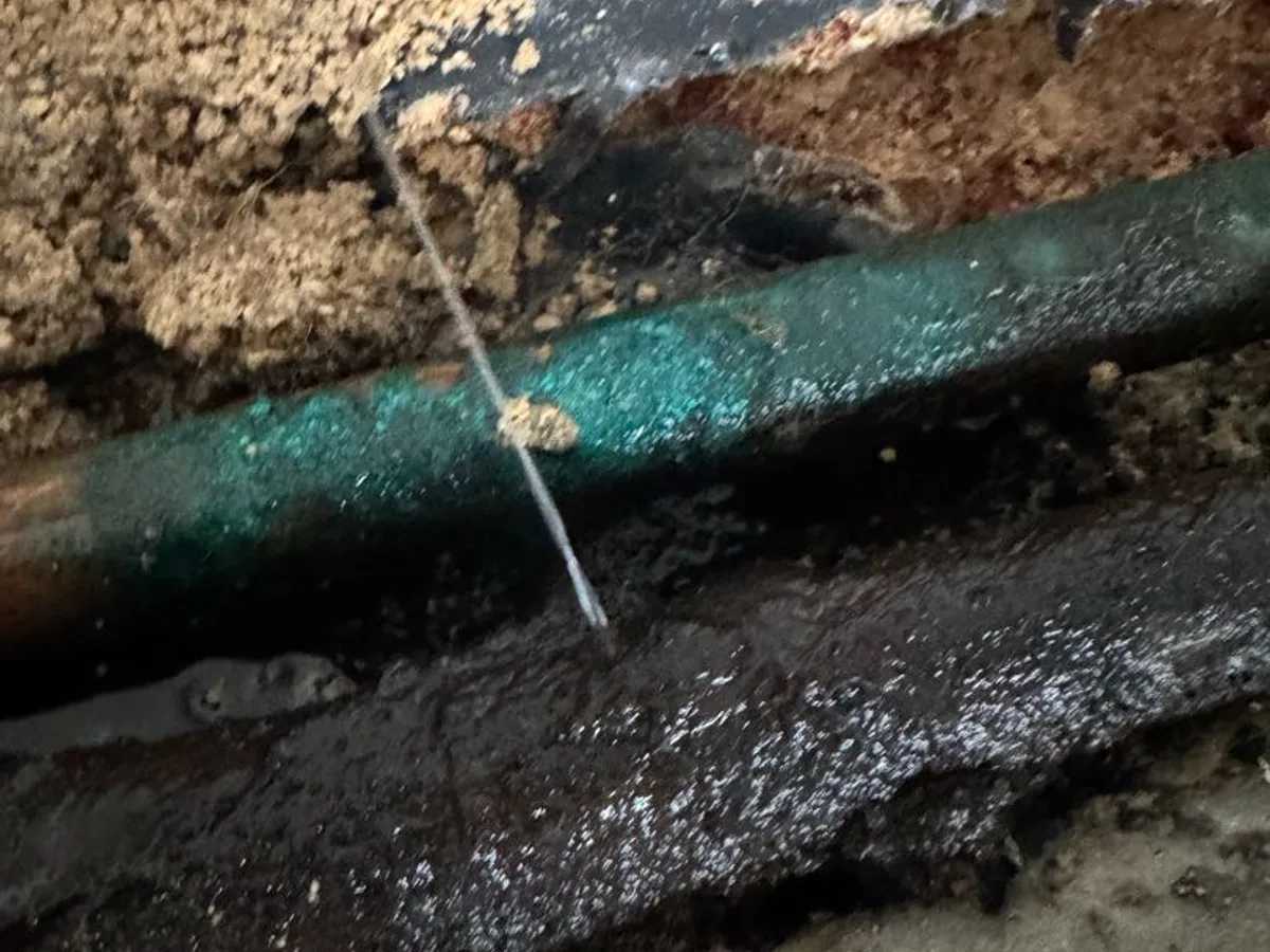 leak located at pinhole in corroded copper heating pipe beneath sandstone floor