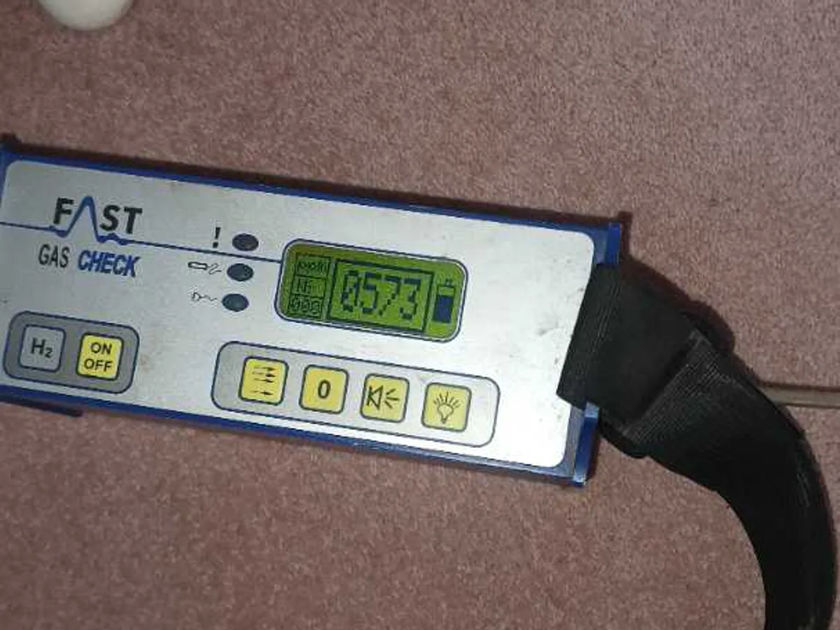 tracer gas detector displaying positive reading on bedroom floor during leak detection