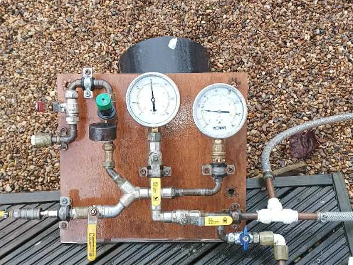 dual-gauge pressure test kit laid out on decking during leak detection