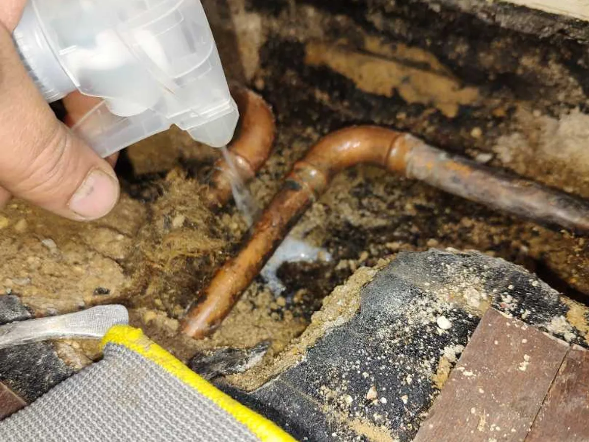 leak located at 15mm copper pipe beneath lifted mosaic parquet flooring in living room subfloor