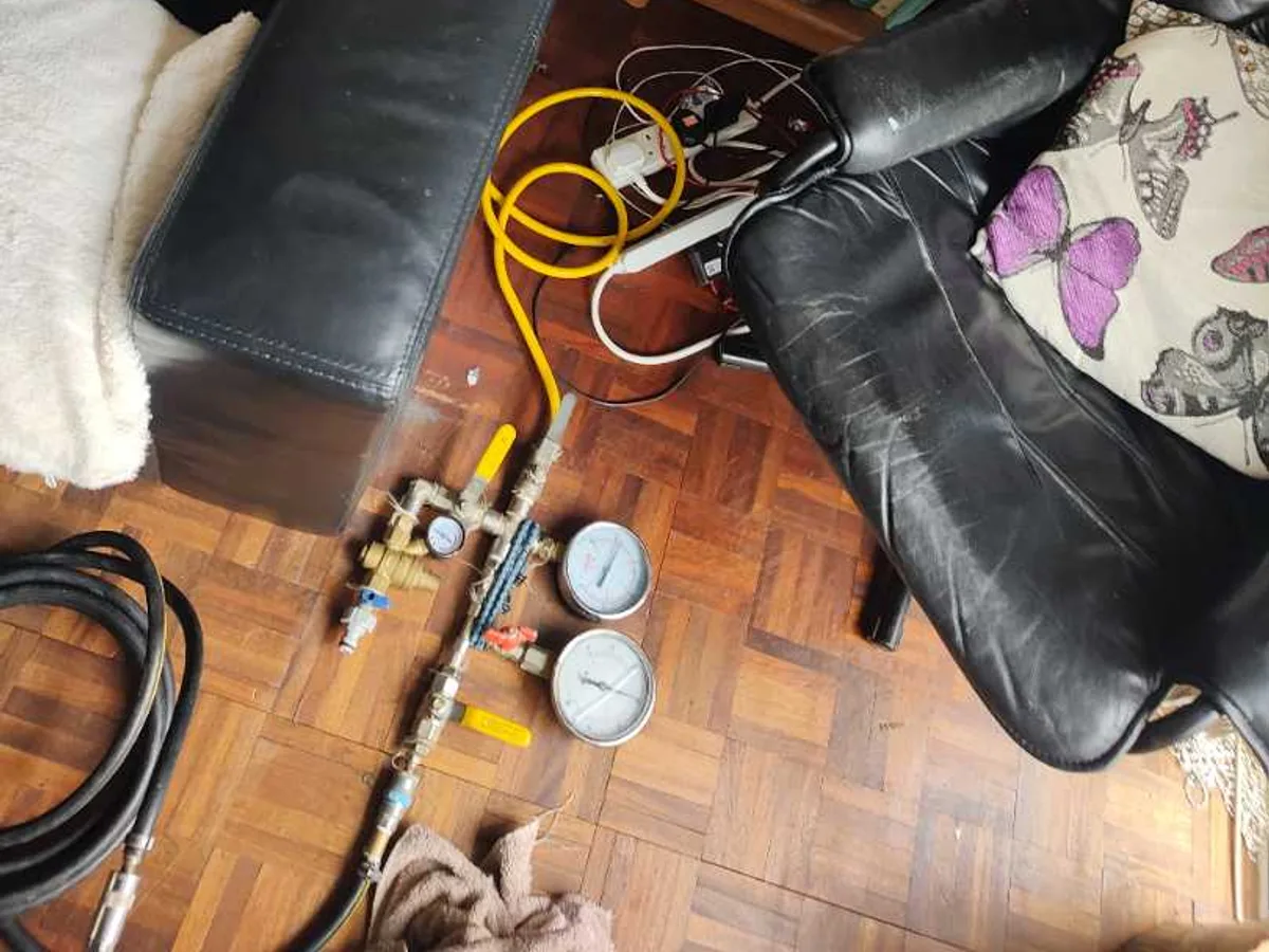 pressure test gauges and air compressor hoses laid on parquet floor during leak detection in living room
