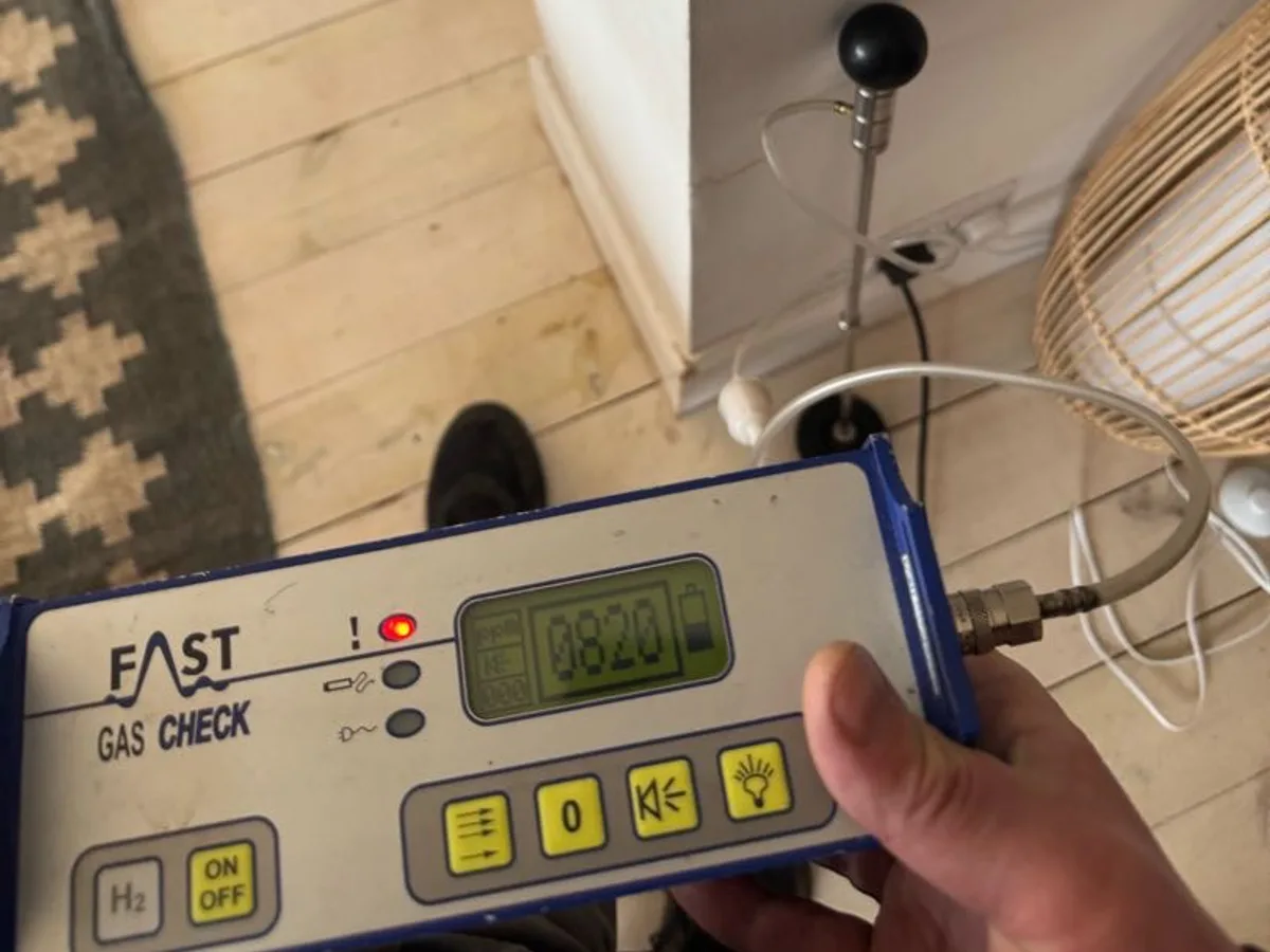 handheld hydrogen gas detector scanning skirting board during leak detection survey